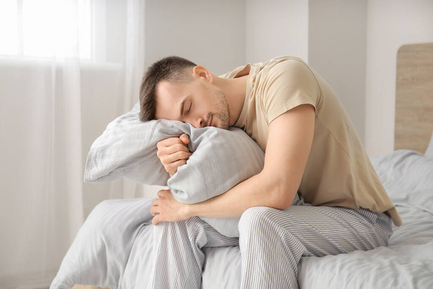 Νεαρός που υποφέρει από στέρηση ύπνου στην κρεβατοκάμαρα - Φωτογραφία, εικόνα