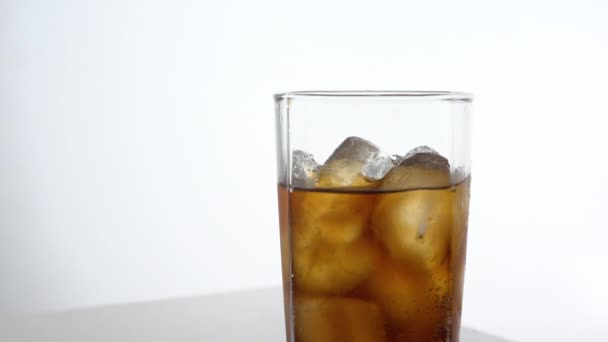 Cold refreshing cola pouring into a glass with ice on white background with space for text. Icy beverage of cool drink with caffeine - Video, Çekim
