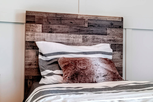 Sänky tyynyt vastaan koriste puinen pääty vastaan valkoinen paneeli seinään - Valokuva, kuva