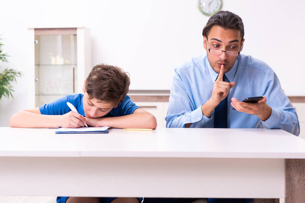 Drukke vader helpt zijn zoon voor te bereiden op examen - Foto, afbeelding