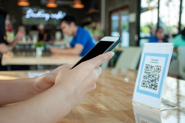 Women's hands are using  the phone to scan the qr code to select food menu. Scan to get discounts or pay for food. The concept of using a phone to transfer money or paying money online without cash. - Photo, Image