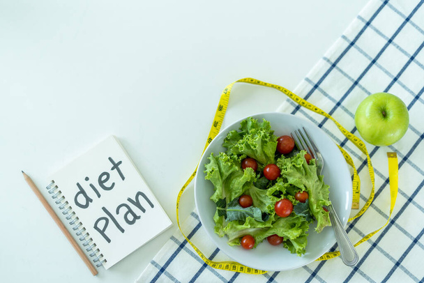 食事計画または食事管理プログラムとテープ測定マネキンプログラム。新鮮な果物や野菜のサラダを食べることを選択減量の食事療法。国会計画とデトックスの概念 - 写真・画像