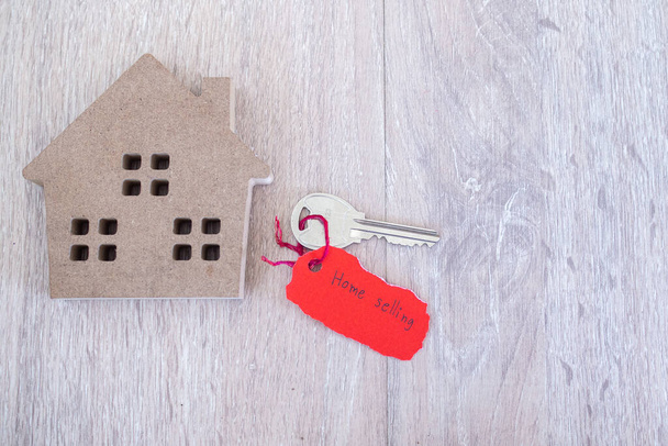 Key and red torn paper with house sales message on wooden background. Concept of selling home - Photo, Image