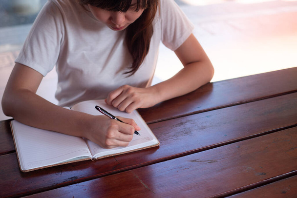 obraz kobiety piszącej na pustym notatniku na stole. - Zdjęcie, obraz