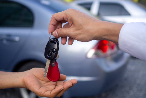 İş adamının arabayı vermesi ya kiralık ya da araba arkaplanındaki müşteriye satması için arabanın anahtarını verir. Satıcının para alması ve arabanın anahtarını imza sözleşmesinden sonra müşteriye vermesi.. - Fotoğraf, Görsel