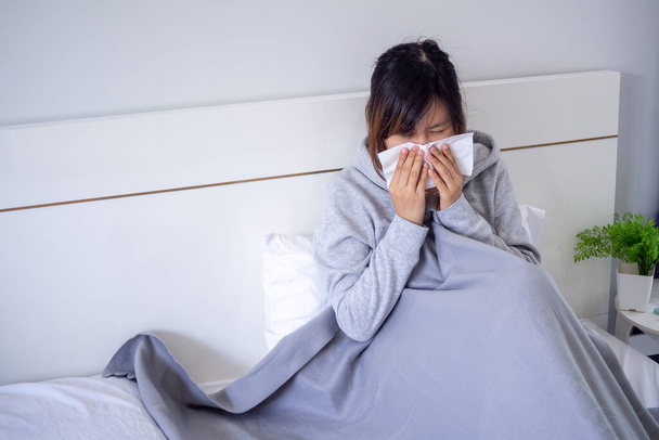 Beteg nő fújta az orrát a takaró alatt ülve. Láz szezonális fertőzés allergia az ágyban a házban. - Fotó, kép