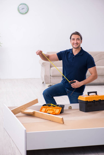 Young male contractor installing furniture at home - Foto, imagen