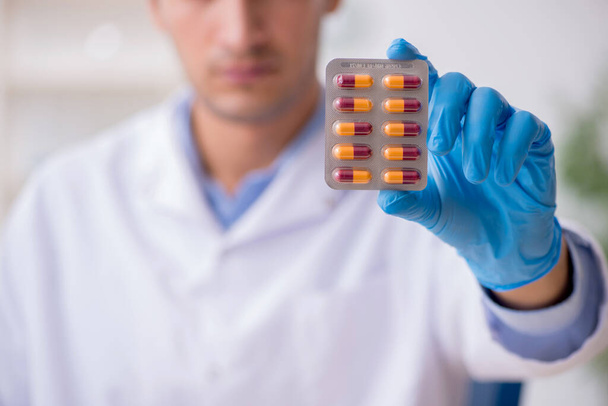 Young male lab assistant in drug synthesis concept - Photo, Image