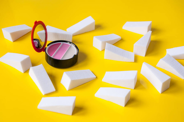 Lots of white triangular sponges and lip gloss on a yellow background - Foto, immagini