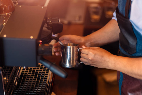 Barista steaming milk in the pitcher with coffee machine for  preparing to make latte art. - Foto, immagini