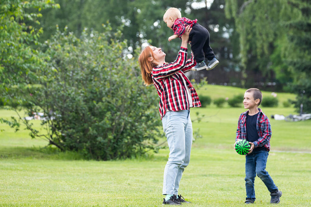 Милые веселые два мальчика брат ребенок с матерью играть на открытом воздухе в парке. Счастье и гармония семейной жизни. Отличный семейный отдых. Мать и сын проводят вместе праздники
. - Фото, изображение