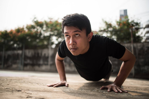 Close-up image of a young sportsman doing push-ups outside - Photo, Image