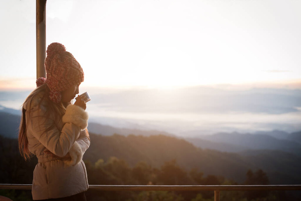 Mujer joven está disfrutando de una taza de café al aire libre con hermosa vista de las montañas
  - Foto, Imagen