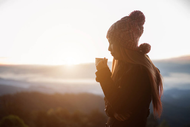 Νεαρή γυναίκα απολαμβάνει καφέ έξω με όμορφη θέα στα βουνά  - Φωτογραφία, εικόνα