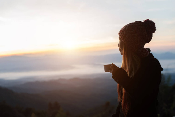 Mujer joven está disfrutando de una taza de café al aire libre con hermosa vista de las montañas
  - Foto, Imagen