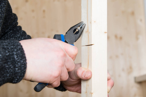 close-up, pliers, pulls a metal nail out of a wooden bar - Fotó, kép