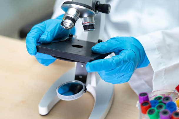 Scientifique asiatique biochimiste ou microbiologiste travaillant avec un microscope en laboratoire. Pour protéger l'épidémie Coronavirus Covid19, bactéries et germes. - Photo, image