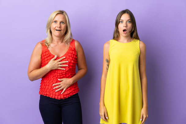 Мама і дочка ізольовані на пурпуровому фоні з подивом і шокованим виразом обличчя. - Фото, зображення