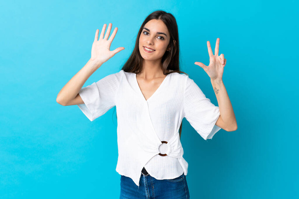 Young caucasian woman isolated on blue background counting eight with fingers - 写真・画像