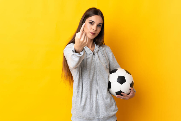 Jonge voetballer vrouw geïsoleerd op gele achtergrond doen komende gebaar - Foto, afbeelding