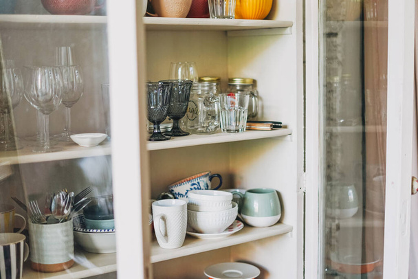 Διαφορετικά κεραμικά πιάτα σε παλιό ξύλινο vintage μπουφέ με διαφανείς πόρτες  - Φωτογραφία, εικόνα