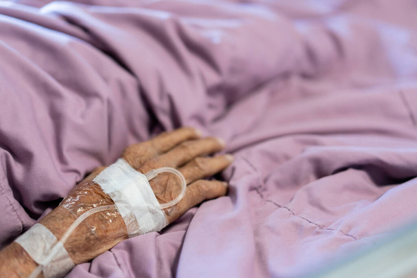 Close up on elder patient's hand with normal saline tube, Elder patient receiving a normal saline through the hypodermic syringe (injector). - Zdjęcie, obraz