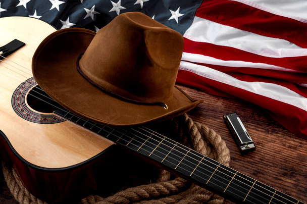 Amerikkalainen kulttuuri, asuu tilalla ja maa muisc konsepti teema cowboy hattu, USA lippu, akustinen kitara, huuliharppu ja köysi lasso puupohjalla vanhassa saluunassa - Valokuva, kuva