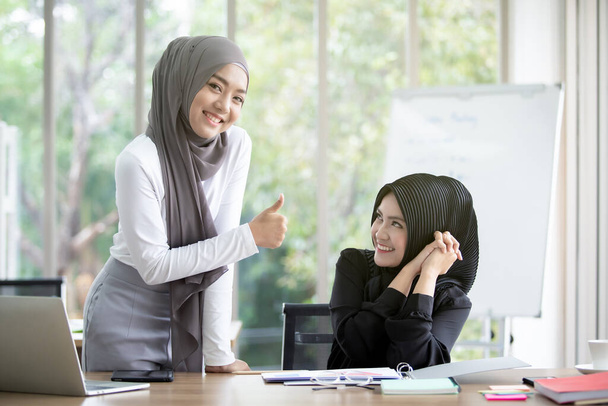 Asian young muslim business woman working together in office. Successful in career path of muslim business woman. Professional colleague and teamwork concept in modern people. - Фото, изображение