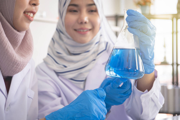 Young Asian Muslim woman doing the chemistry experiment in laboratory close up, woman muslim scientist in laboratory concept. - Foto, Imagem