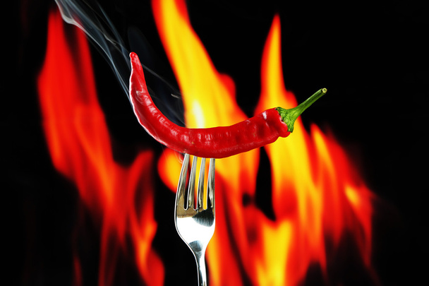 Red hot chili pepper on fork, on fire background - Foto, afbeelding