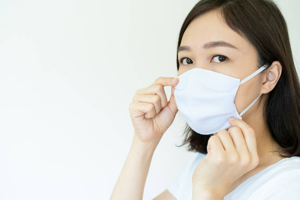 Asian young attractive woman wearing a protective hygiene mask over her face to protect flu and virus. Woman with face mask portrait with copyspace. Covid19 and Coronavirus. - Fotografie, Obrázek
