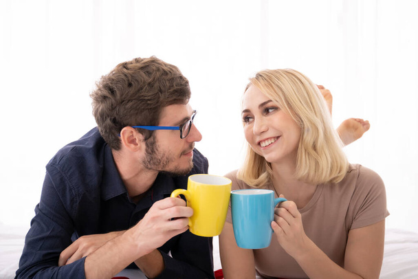 Romantic caucasian young couple enjoy drinking coffee together in the bedroom in morning. Togetherness and relationship of happy young couple concept. - Foto, Bild