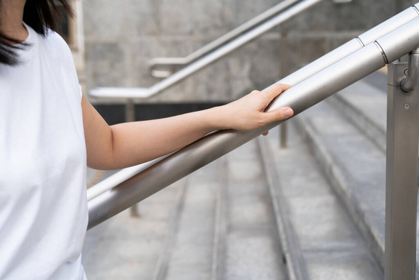 Woman walking on the stair way and grabbing on safety stair rail. Close up shoot on a hand catching a stair rail. Woman aware about safety while walking on the stair way. - Foto, Bild