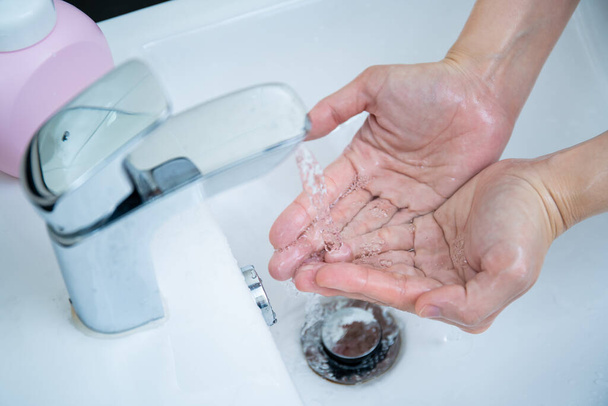 Donna che si lava le mani usando sapone liquido per lavarsi le mani per proteggere dal coronavirus 2019, rischio di flesso del virus COVID-19. Lavare le mani può aumentare l'igiene personale e proteggere dal virus
. - Foto, immagini