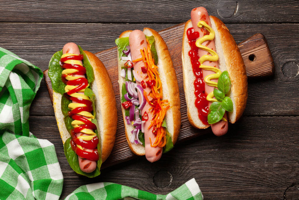 Diverse hotdog met groenten, sla en specerijen op houten ondergrond. Bovenaanzicht. Vlakke plaat - Foto, afbeelding