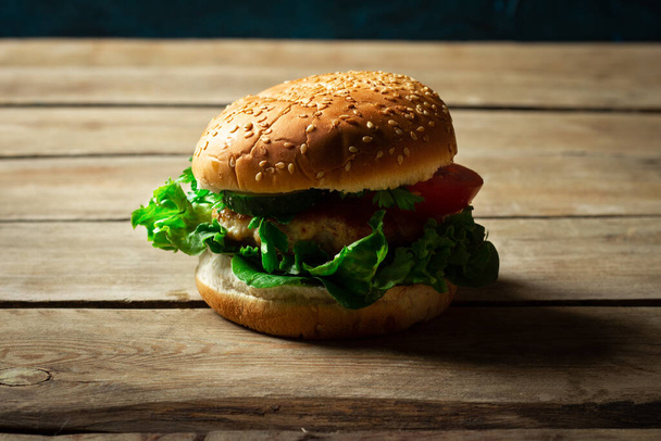 Frisch hausgemachter appetitlich leckerer Burger mit Hühnchen auf Holztisch. - Foto, Bild