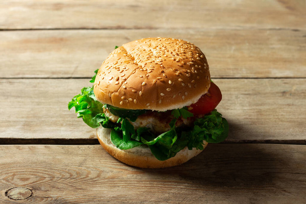 Fresh home-cooked appetizing tasty burger with chicken on wooden table. - Фото, зображення