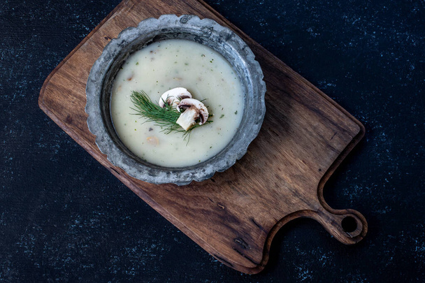 Zupa grzybowa na drewnianym stole z widokiem z góry i ciemnym tłem. Koncepcja żywności wegetariańskiej.  - Zdjęcie, obraz