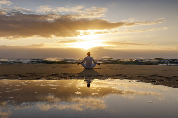 Yoga meditasyon silueti lotus gün doğumu plajı, yoga poziyonundaki insanın su yansıması, farkındalık konsepti. - Fotoğraf, Görsel
