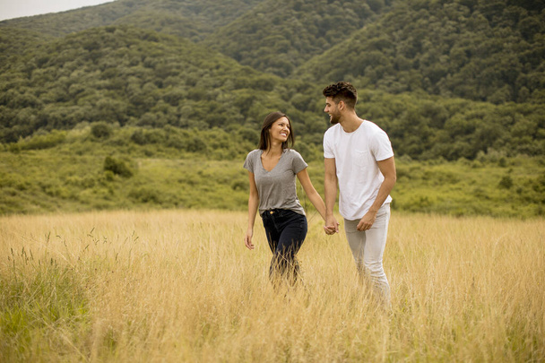 幸せな若いですカップルで愛で歩く草のフィールド上の夏の日 - 写真・画像