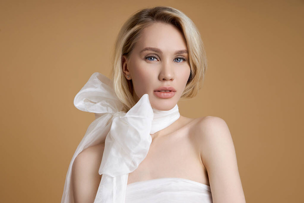 Beautiful blonde woman with a big white bow around her neck - Photo, image