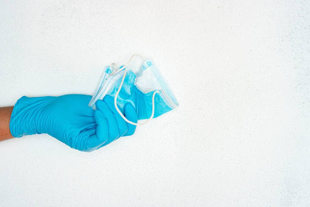 A closeup shot of a person hand in blue medical gloves holding a medical mask near a copy space - Foto, Imagem