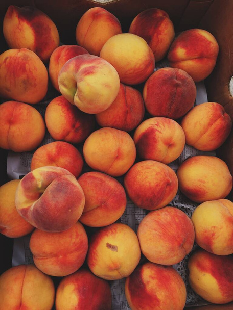 A vertical image of ripe juicy peaches in a box - Valokuva, kuva