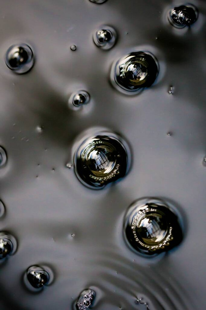 A vertical macro shot of rain drops in water surface - Foto, afbeelding
