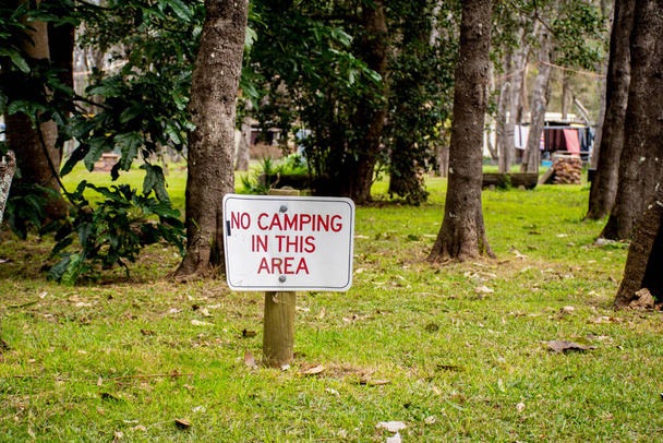 Brak kempingu w tej okolicy znak na zielonej trawie otoczony drzewami - Zdjęcie, obraz