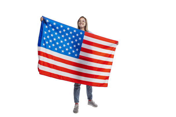 A smiling young girl with an American flag in her hands. Independence Day and Patriotism. Isolated on a white background. - Foto, Imagem