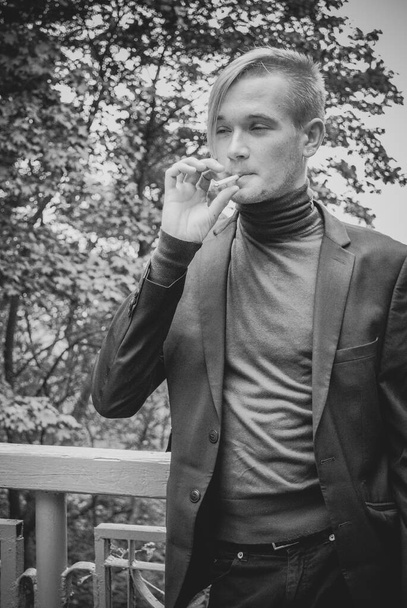 Молодой парень ходит и курит, студент на городской улице, в колледже или университете время образа жизни
 - Фото, изображение