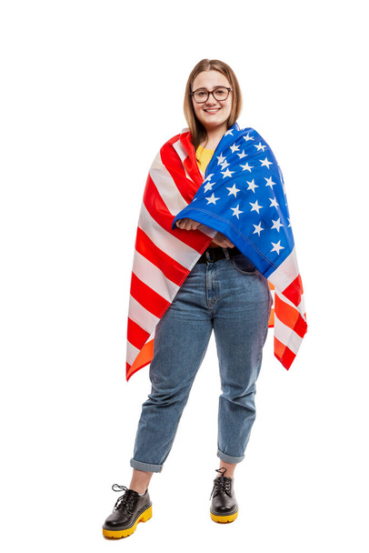 Smiling young girl in glasses with an American flag in her hands. Independence Day and Patriotism. Isolated on a white background. Vertical. - Foto, Imagen