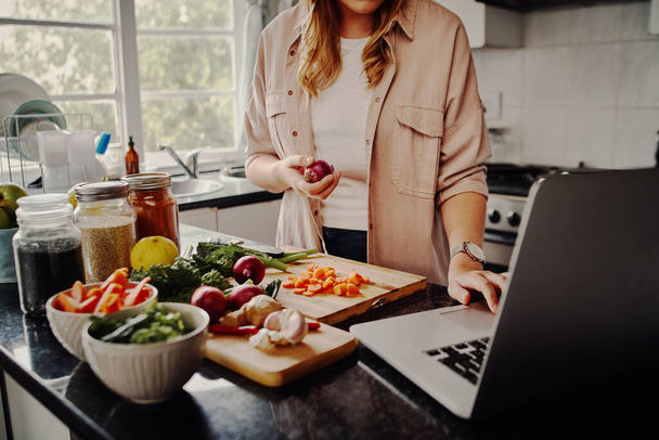 Young female blogger searching online browsing for recipes to prepare salad of fresh vegetables and post on social media in vlog - new hobby during isolation - 写真・画像