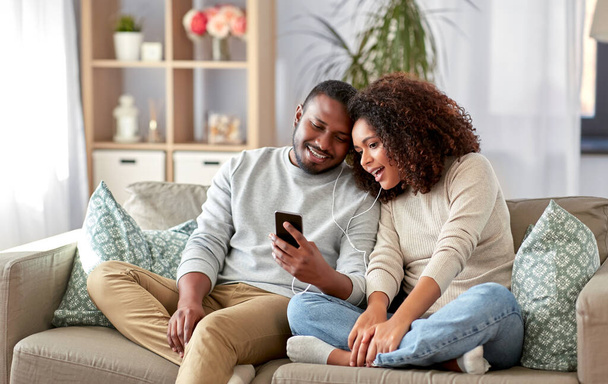 happy couple with smartphone and earphones at home - Zdjęcie, obraz